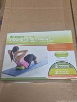 Front of sealed box showing kit name, image of user on green therapy ball and workout details