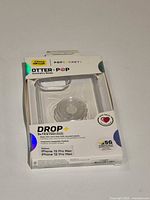 Front of unopened OtterBox DROP+ Symmetry Series clear case box showing product and PopGrip