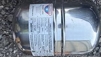 Label side of stainless expansion tank showing capacity and manufacturer info