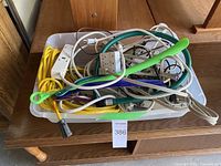 Top view of bin showing yellow cord, power strips, cube adapter, assorted cords