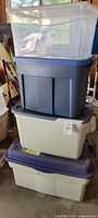 Stack of four plastic storage bins in varying colours and sizes showing overall condition and lids