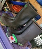 Both pairs of black rubber boots side by side on bin