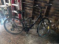 Full left-side view of black DCO City Class bicycle with rear basket and pump visible behind front wheel
