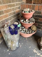 overall view showing vase filled with bottles beside stacked planters filled with rocks