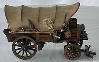 Side view of wood Conestoga wagon with canvas cover and pioneer tools
