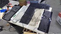 Six keyboards stacked on table showing overall quantity and color variety