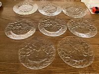 All eight clear glass plates displayed on wooden surface