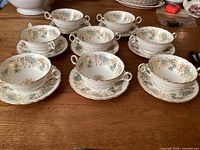 Set of eight soup bowls on saucers displayed on table