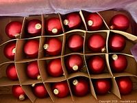 Top view of divided box showing all 24 red ornaments with gold caps