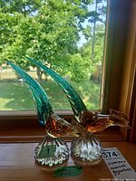 Both bird figurines on windowsill showing colors and sticker