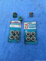 Two blister packs of plug fuses and three fuse adapters on blue background