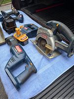 Group view of tools on tailgate: circular saw, jig saw, charger, battery