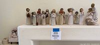 Full group of Willow Tree figurines on mantle showing quantity and variety