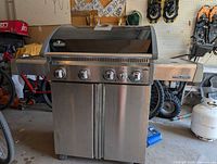 Front view of Napoleon Triumph grill showing four control knobs, cabinet doors, overall condition