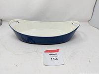 Top angled view of oval blue exterior, white interior dish with handle cut-outs