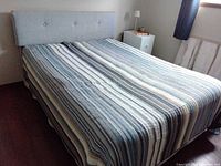 Full bed with striped cover showing headboard