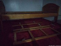 Twin maple bed frame assembled with headboard and footboard in place, side rails and ladder sections laid out