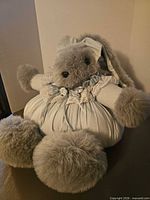 Full view of gray plush bunny in blue dress