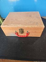 Front view showing gingham exterior, latch, red handle
