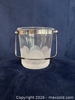 Front view of clear glass ice bucket showing frosted petal pattern and metal handle