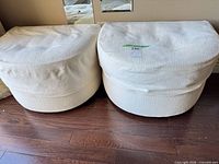 Two white upholstered ottomans side by side