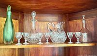 All items on shelf: three decanters, pitcher, six glasses