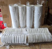 Stacked sleeves of 32 oz paper containers and two sleeves of matching lids