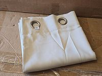 Folded off-white curtain panel showing two metal grommets