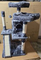Full view of grey plush cat tree showing perches, cubby, posts and scratch panel