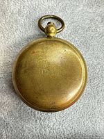 Front of closed brass compass showing U.S.C.E. engraving and ring