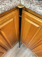 Full cane leaning against cabinet showing black shaft and brass top