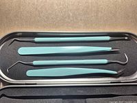 Four teal-handled precision picks in metal case