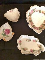 Front view of four rose-decorated porcelain dishes