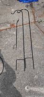 Full view of three black steel shepherd's hooks lying on paving