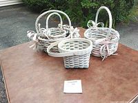 Three pastel wicker baskets and one square slat basket grouped on table
