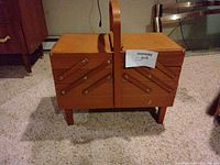 Closed wooden cantilever sewing box on legs