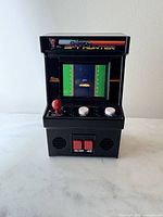 Front view showing screen on, joystick, buttons, speaker grilles, power switch
