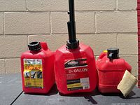 Front view of all three red fuel cans showing labels and spout
