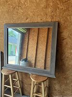 Front view of mirror leaning on stools showing full frame and reflection