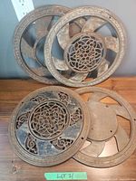 Four cast iron round register grates grouped on table