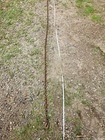 Full length view of rusty steel chain alongside measuring tape on ground
