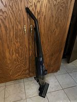 Full view of Hoover Quik-Stick vacuum leaning against cabinet