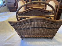 Front side view highlighting wicker weave, black trim, curved top rails, rattan legs