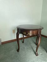 Front view of oval end table showing drawer, brass hardware and cabriole legs