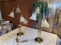 Both lamps unplugged showing brass bases, vertical rods, frosted glass bell shades