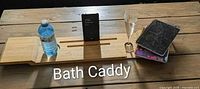 Full view of bamboo bath caddy on table staged with bottle, phone, glass and notebooks