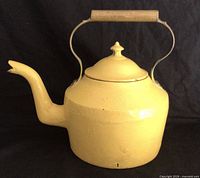 Full left profile of yellow cast iron kettle showing lid, handle, and spout