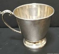Front view of sterling silver baby cup showing body, base, and handle