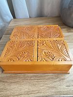 Top view of carved wooden box showing four separate sliding lids with foliate carving