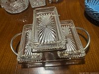 Overall view of three glass dishes seated in silver-plated stand on tabletop
